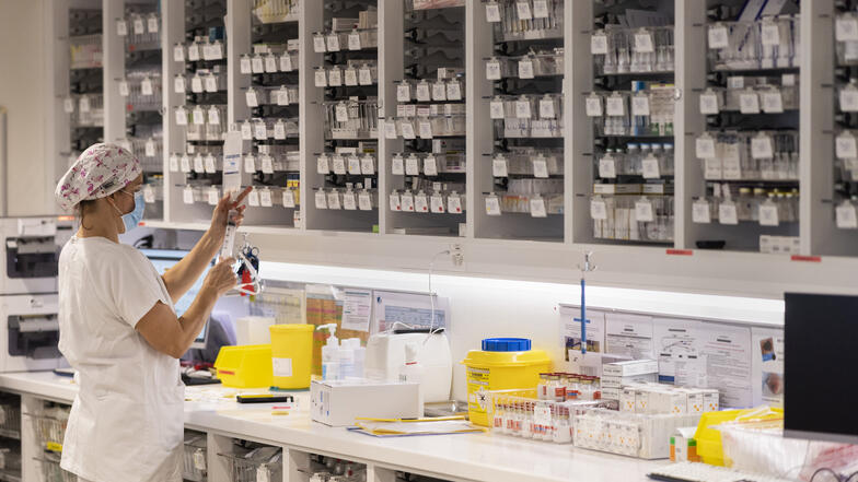 Une soignante devant une armoire remplie de médicaments
