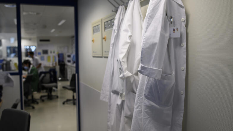 Un couloir au mur duquel sont accrochées des blouses blanches