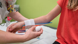 Nahaufname: Ärztin legt eine Schiene an Arm eines Kindes
