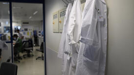 Un couloir au mur duquel sont accrochées des blouses blanches