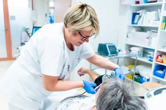 Eine Pflegerin legt einer Patientin eine Blutdruckmanschette an