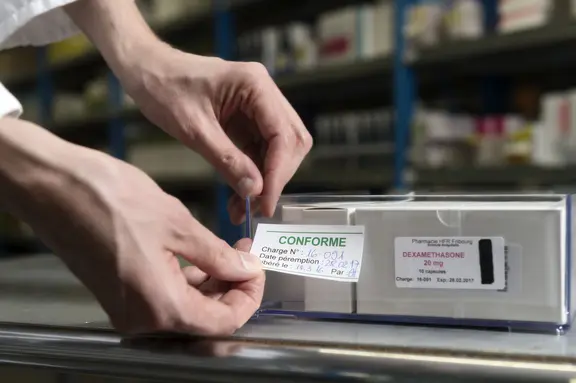 Un pharmacien colle une étiquette "conforme" sur un médicament